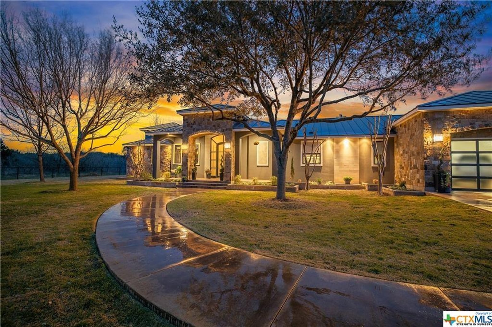 Stone home at sunset sold by The Allan Home Group